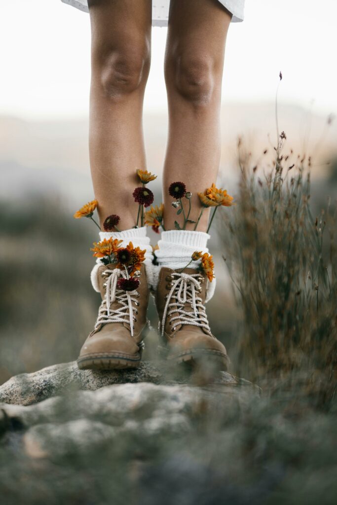 pexels-photo-7866283-7866283 Artistic capture of legs in boots adorned with wildflowers, blending fashion and nature.