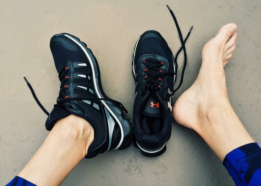 run-fitness-workout-train-163535-163535 A pair of black sneakers next to bare feet on a gray surface.